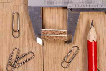 Pencils, paper clips and calipers on a wooden surface. Workshop scale models. Print for design...