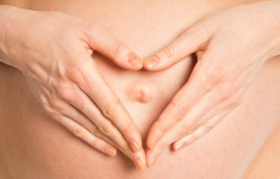Pregnant belly and heart-shaped hands