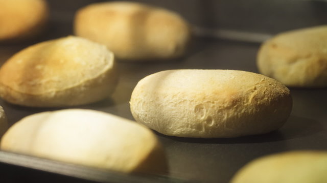 Time lapse of biscuits baking on a cookie sheet in an oven; shallow focus on one biscuit. 