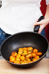 Young woman frying potatoes