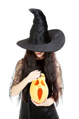 Young brunette witch with pumpkin on a white background