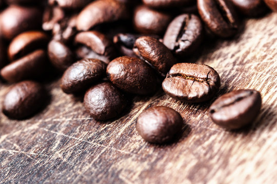 Coffee beans on grunge wooden table top view image, macro