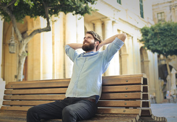 Relaxed man daydreaming on a bench