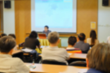 Motion blur of speaker present project with some audience in a meeting room