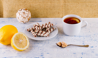 Tubules wafer and tea with a lemon on an old table