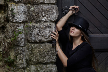 Girl model at a brick, old wall in a black hat.