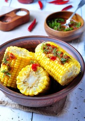 boiled corn with hot tomato sauce, herbs, salt and spices