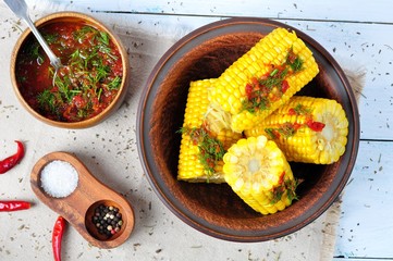 boiled corn with hot tomato sauce, herbs, salt and spices