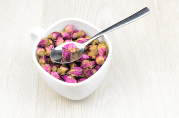 tea roses in a white cup on wooden table