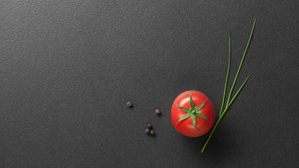 red tomato with green onion on black