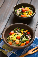 Baked vegetables (zucchini, onion, cherry tomato, broccoli, carrot, sweet corn, green bean, chard), photographed with natural light (Selective Focus, Focus one third into first dish)