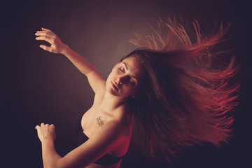 Young brunette caucasian woman dancing and her hair flowing through the air