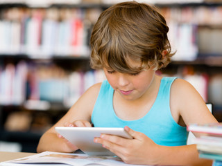 Primary school boy with tablet in library