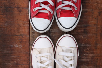 Original Valentine's Day love concept with red and white sneakers. Studio shot on a wooden floor background.