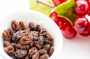 Raisins in bowl with red grapes.