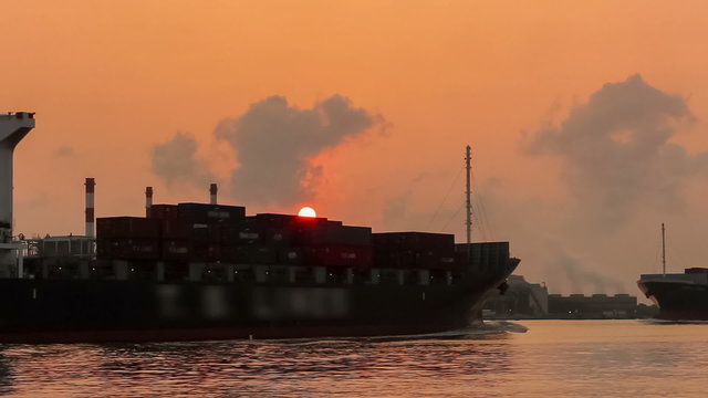 Cargo ship at sunrise on electric power station background