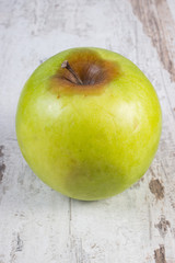 Spoiled apple on old wooden white table
