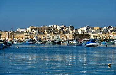 Fototapeta na wymiar Traditional Maltese village with reflection in the sea, Malta