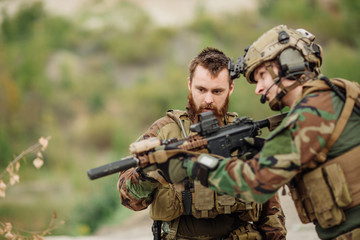 Fototapeta premium us Instructor with soldier aiming rifle at firing range