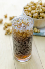 Cola with Ice and Popcorn on a wooden background