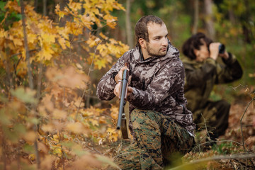 Fototapeta na wymiar Instructor with woman hunter aiming rifle at firing nature