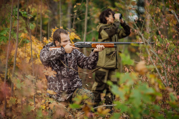 Instructor with woman hunter aiming rifle at firing nature