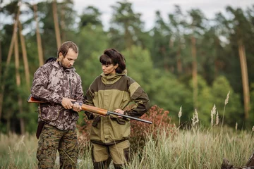 Papier Peint photo Lavable Chasser Instructor with woman hunter aiming rifle at firing nature