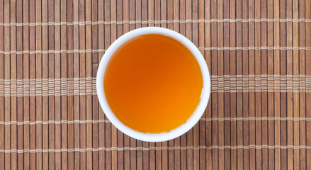 Cup of Chinese hot tea on bamboo mat background