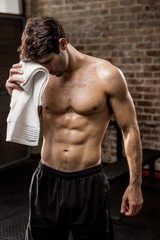Muscular man wiping his face with towel