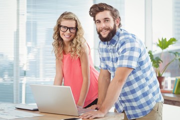 Portrait of smiling man and woman while standing at desk 