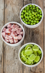 three white bowls with chopped bacon,leek,peas,
