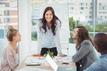 Fototapeta premium Portrait of smiling woman while coworkers looking at her 