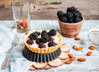 tartlets with cream cheese and blackberry on a light wooden.tabl
