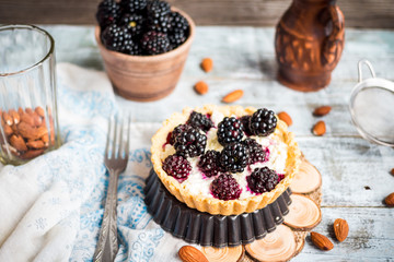 tartlets with cream cheese and blackberry on a light wooden.tabl
