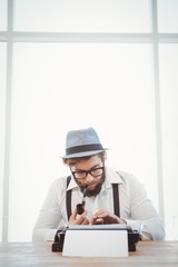 Hipster smoking pipe while working at desk