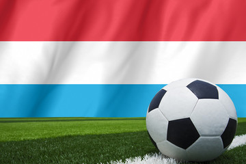 Fototapeta premium Soccer ball and national flag of Luxembourg lies on the green gr