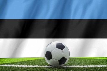 Soccer ball and national flag of Estonia lies on the green grass