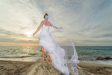 YOung bride by the sea at sunset