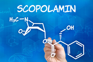 Hand mit Stift zeichnet chemische Strukturformel von Scopolamin