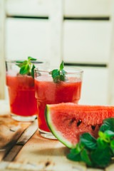 two watermelon smoothie and fresh on a light wood background. selective focus to mint