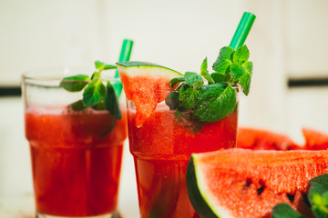 two watermelon smoothie and fresh on a light wood background. selective focus to mint