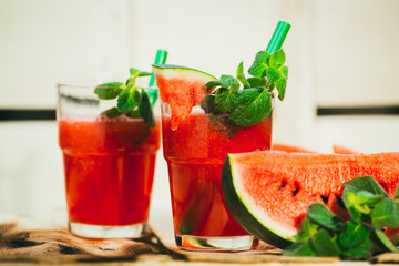 two watermelon smoothie and fresh on a light wood background. selective focus to mint