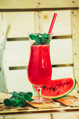 watermelon smoothie and fresh on a light wood background with red straw. selective focus to mint