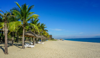 Beautiful sandy beach with parasol and sun lounger : Cua Dai Beach, Hoi An, Vietnam.
