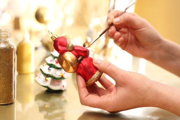 św. Mikołaj  ręcznie malowana bombka choinkowa. Kobieta maluje bombki pędzelkiem