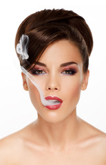 Woman blowing smoke against white background.