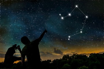 Libra constellation of zodiac on night sky. Astrology concept. Silhouettes of adult man and child observing night sky.