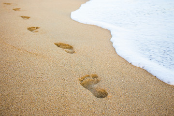 footprints in the sand and sea wave