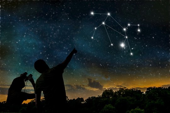 Leo or Lion constellation of zodiac on night sky. Astrology concept. Silhouettes of adult man and child observing night sky.