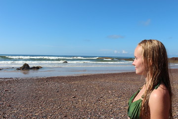A portrait of young woman staring into the distance on the Atlantic ocean beach.

